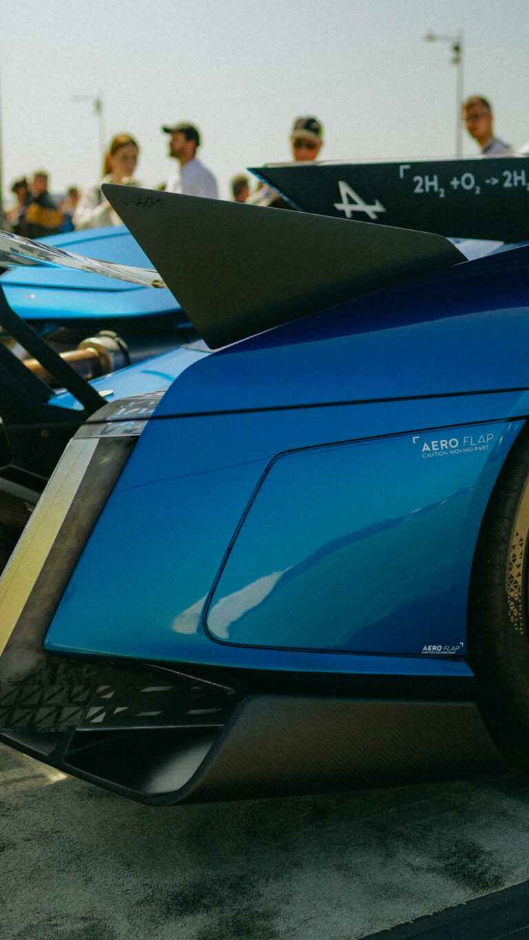 Photographie détaillée d’une Alpine, bleue capturée lors d’un événement automobile. Image mettant en valeur les lignes sportives et le design iconique de la voiture française.