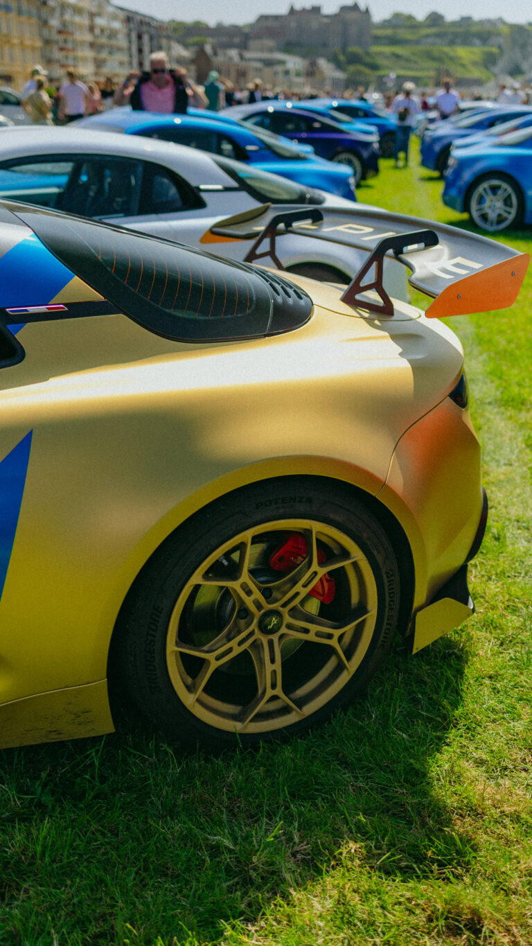 Photographie détaillée d’une Alpine A110 bleue capturée lors d’un événement automobile. Image mettant en valeur les lignes sportives et le design iconique de la voiture française.